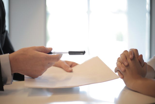 Person-handing-someone-a-contract-and-pen