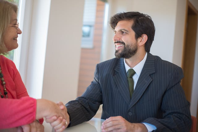 a-property-manager-in-a-dark-suit-shaking-hands-with-someone-in-pink