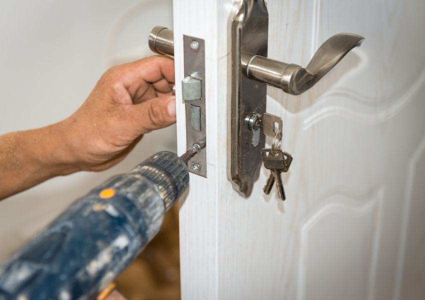 contractor-using-a-drill-to-fix-a-lock-on-a-door
