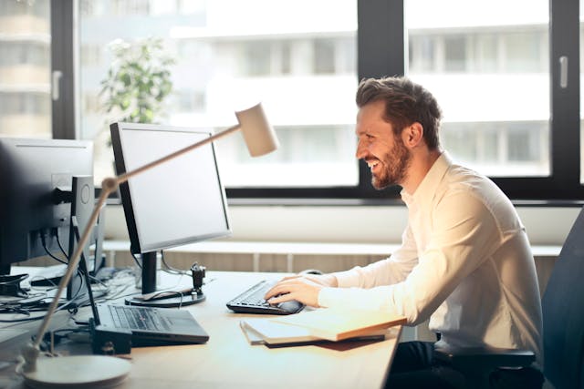 a person smiling while sitting at their desk