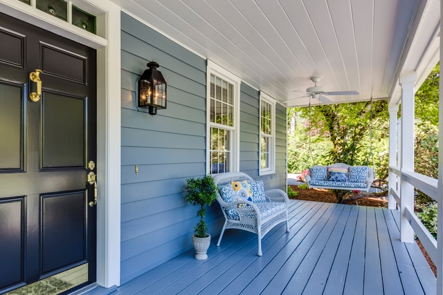 A blue porch with a small outdoor couch